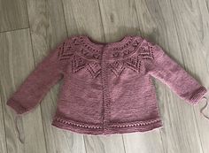 a pink knitted sweater laying on top of a wooden floor