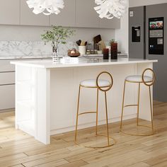 two white stools sitting in front of a kitchen island with lights hanging from it