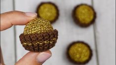 a hand holding a small crocheted ball with gold glitter on it's side