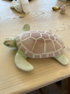 a clay turtle sitting on top of a wooden table