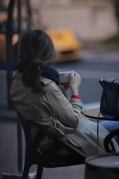 a woman sitting on a chair holding a cup