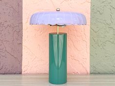 a green lamp sitting on top of a table next to a pink and yellow wall