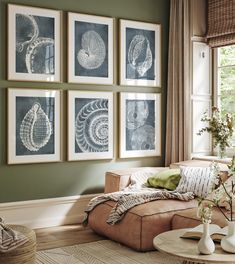 a living room with green walls and pictures on the wall above the couch, along with vases filled with flowers