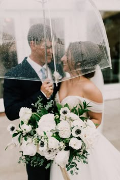 a bride and groom kissing under an umbrella