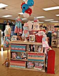 an assortment of children's clothing on display in a store with wooden flooring