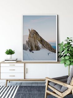 a chair sitting in front of a white wall with a large poster hanging above it