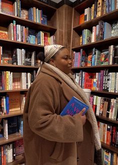 a woman standing in front of a bookshelf holding a book