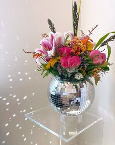 a disco ball vase filled with flowers and greenery