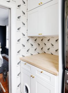 a kitchen with black and white wallpaper, wood counter top and wooden flooring