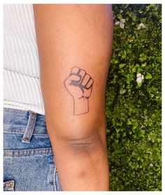 a woman's arm with a tattoo on it that has a fist in the middle