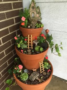 three tiered planters filled with plants and miniature garden accessories on the side of a house