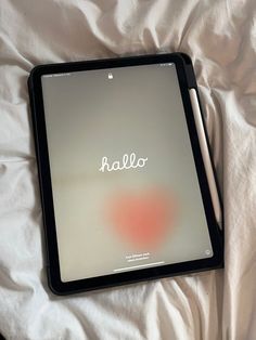 an ipad with the word hello written on it sitting on top of a white sheet