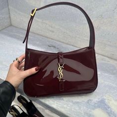 a woman's hand holding onto a red purse