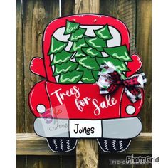 a red truck with christmas trees on it is hanging from the side of a wooden fence