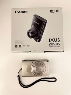 a camera sitting on top of a white table next to a box with it's lid open