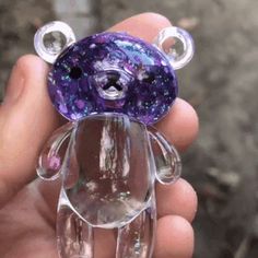 a hand holding a purple teddy bear with bubbles