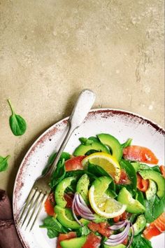 a white plate topped with sliced up vegetables and avocado on top of a table