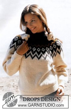 a woman is standing on the beach wearing a sweater