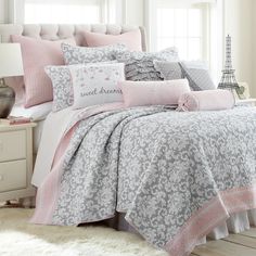 a bed with pink and grey comforters in a bedroom