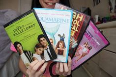 a woman holding four dvd's in her hands