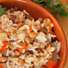 a bowl filled with rice and beans on top of a wooden table next to vegetables