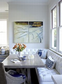 a living room with white furniture and paintings on the wall