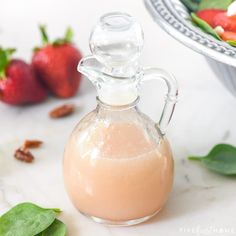 a glass bottle filled with liquid sitting next to some strawberries and other food items