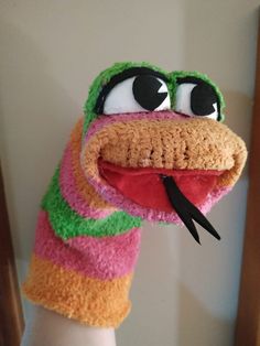 a hand that has a knitted animal glove on it's arm, with eyes and mouth wide open