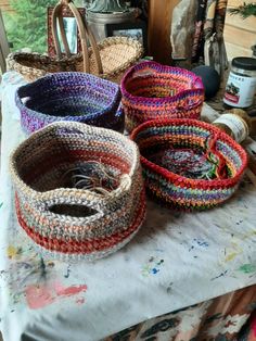 three baskets sitting on top of a table covered in paintbrushes and paper towels