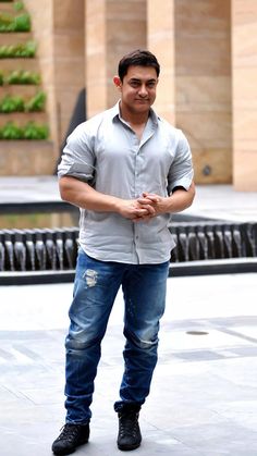 a man standing in front of a fountain with his hands together and looking at the camera