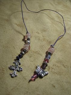 two necklaces with cross charms on them sitting on a table top next to a cord