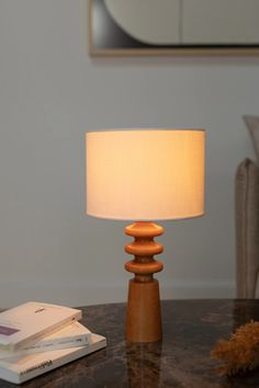 a table lamp sitting on top of a wooden table next to a book and a mirror