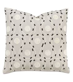 a white pillow with black and white circles on the front, along with a light gray background