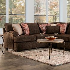 a living room with brown couches and pillows on the floor in front of large windows