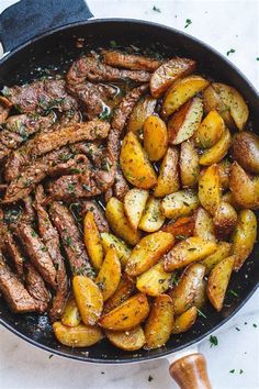 steak and potatoes in a skillet with herbs on the side for garnish