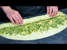 a person is rolling out some food on a large piece of bread that's ready to be put in the oven