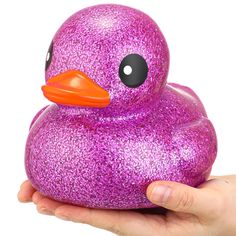 a hand holding a purple glittered rubber ducky with an orange beak and black eyes