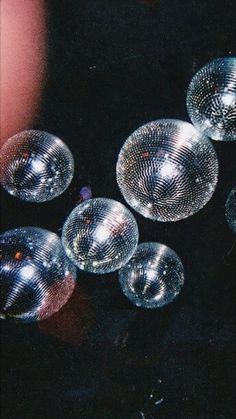 several disco balls sitting on top of a black table next to a person's hand