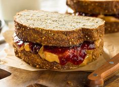 a peanut butter and jelly sandwich on top of brown paper next to a wooden spoon