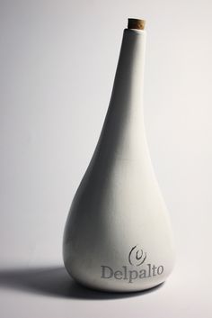 a white vase sitting on top of a table next to a wooden stick in the shape of a pear