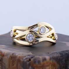 two gold rings with diamonds sitting on top of a rock