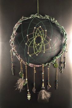 a dream catcher with feathers and beads hanging from it's side on a black surface