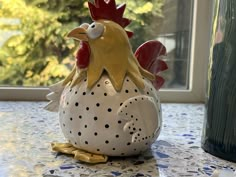 a ceramic chicken sitting on top of a table next to a vase