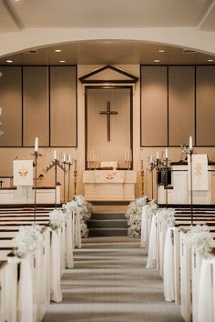 a church filled with pews covered in white flowers and candles next to the alter