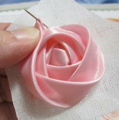 a person is making a flower out of fabric with a sewing needle on top of it