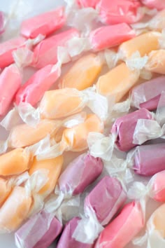 several different colored candies on a white plate with plastic wrappers around them,