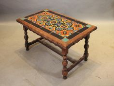 an old wooden table with colorful tiles on it's top and legs, against a white background