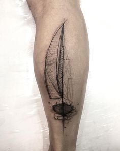 a black and white photo of a man's leg with a sailboat tattoo on it