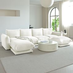 a large white couch sitting on top of a living room floor next to a window