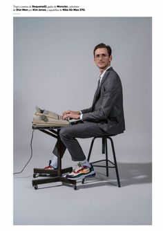 a man sitting at a desk with his feet up on a chair and holding a laptop